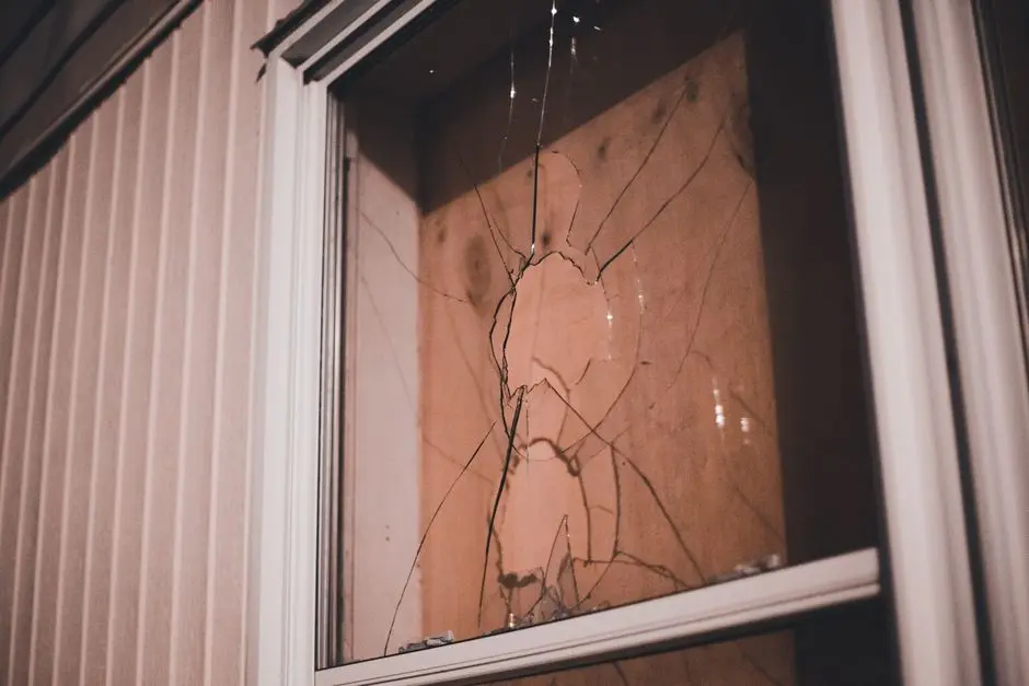 Detailed view of a cracked window pane at night, highlighting textures and reflections.